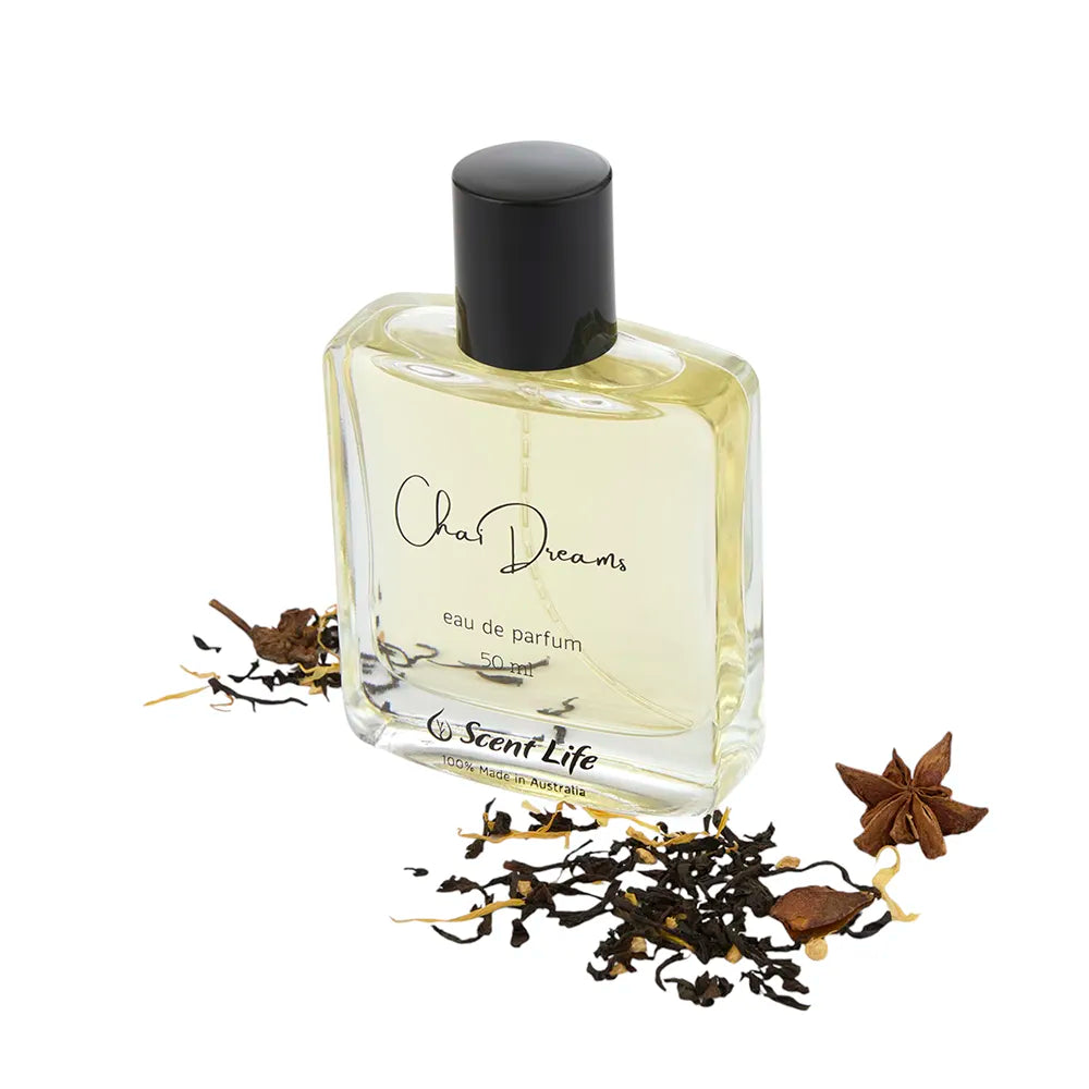 A 50ml bottle of Chai Dreams eau de parfum, complete with a black cap and surrounded by scattered cinnamon spice, star anise, and dried herbs. The Scent Life brand is elegantly displayed at the bottom of the bottle.