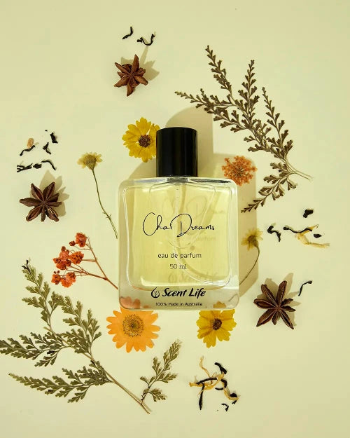 A glass bottle of Chai Dreams eau de parfum (50 ml) from Scent Life is artfully arranged among dried flowers, star anise, and black tea leaves on a soft beige background, evoking hints of herbal nuances. The label proudly displays "100% Made in Australia.