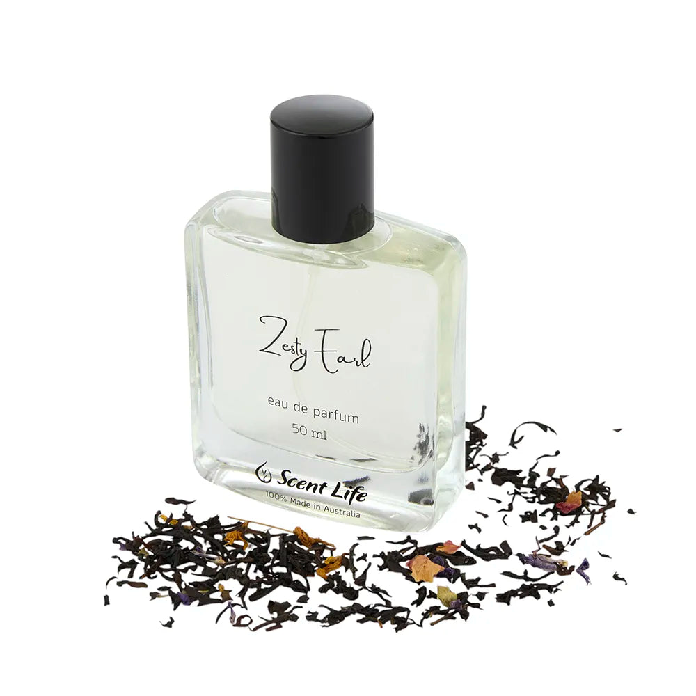 A 50 ml bottle of Zesty Earl eau de parfum by Scent Life is gracefully showcased among scattered Earl Grey tea leaves. The clear bottle, paired with a black cap, reveals the pale liquid inside, suggesting invigorating citrus notes that embody a refreshing blend.